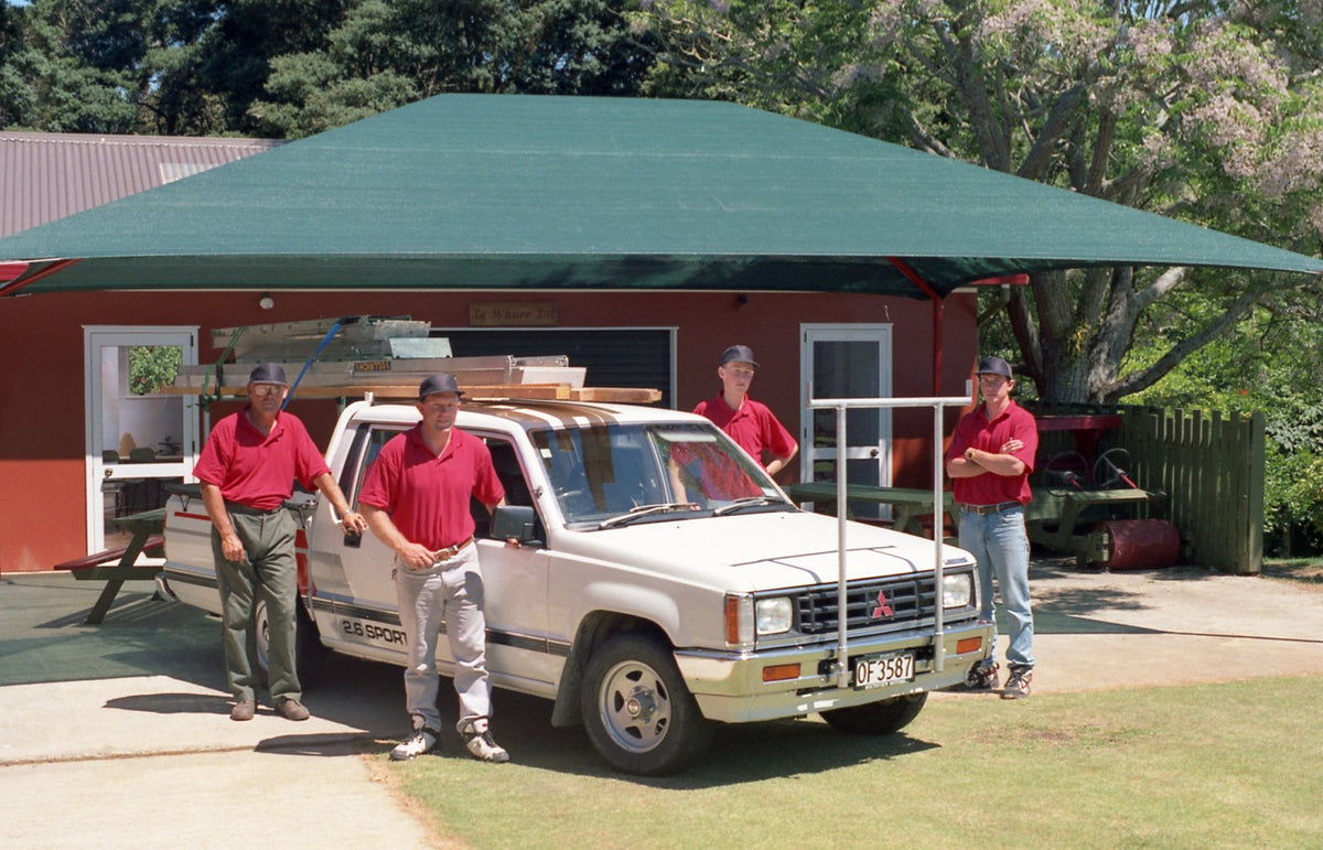 Early Shade Sail installation team beside a green Shade Sail and work vehicle.