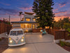 Koru Clips hold string lights along a shade sail above a house at sunset, with a vintage Volkswagen van and scooter in the foreground.